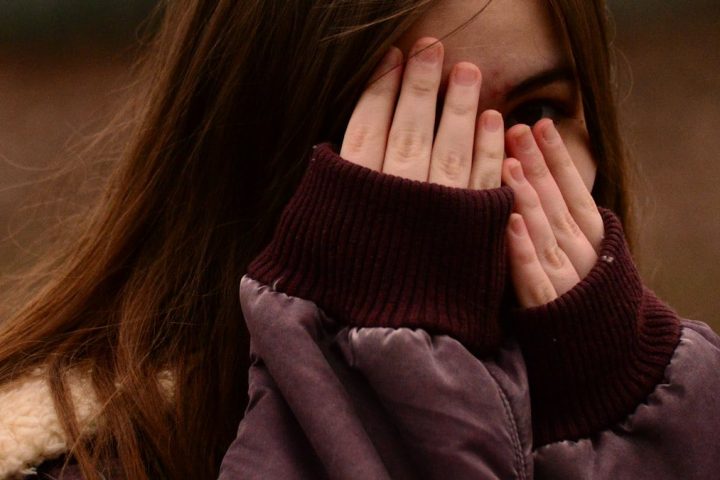 woman in purple sweater covering her face