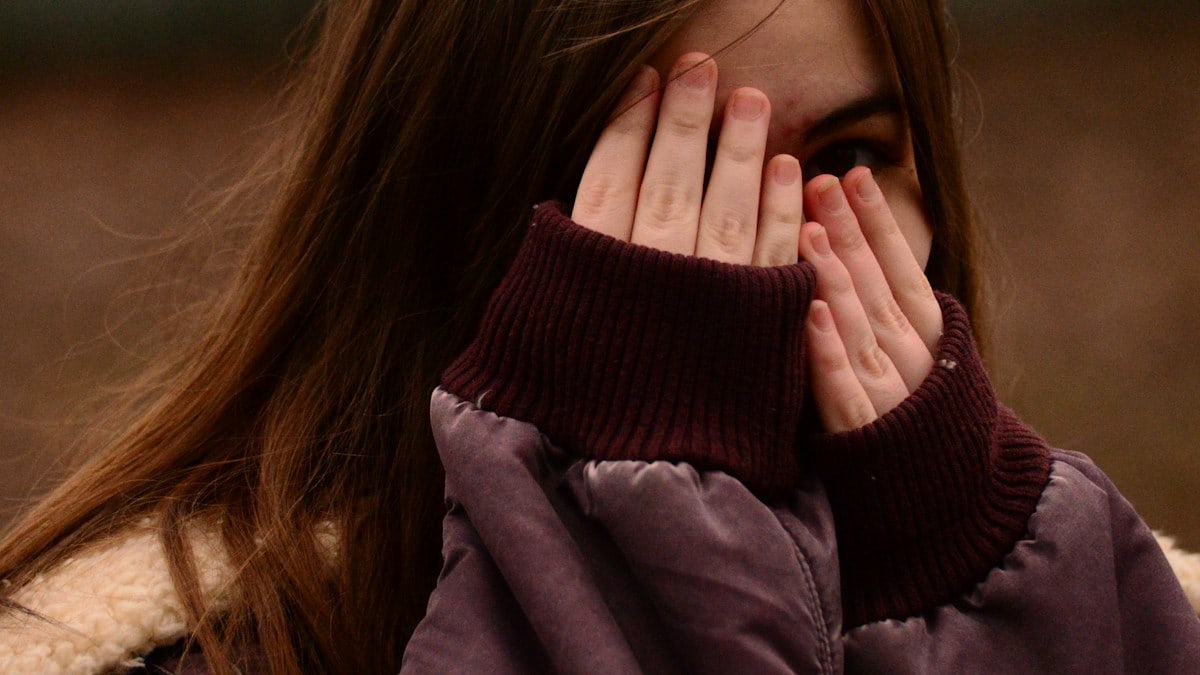 woman in purple sweater covering her face